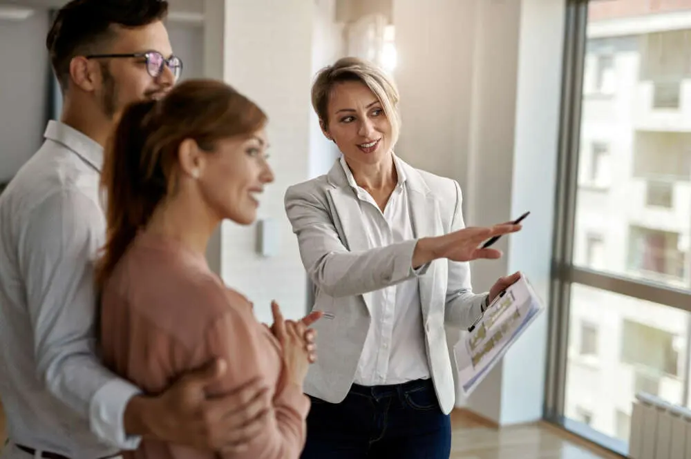 Agente inmobiliario sonriente hablando pareja interesada comprar casa nueva